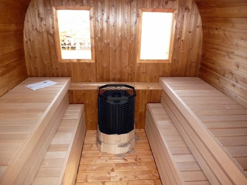 Innenraum einer Holzsauna mit Sitzbänken und Ofen