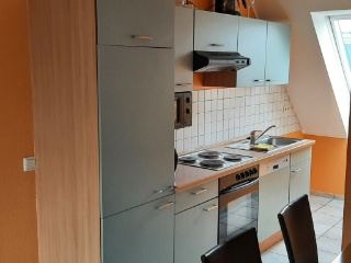 Küche der Ferienwohnung Luna mit grauen Schränken und orangefarbener Wand