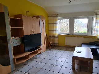 Wohnzimmer der Ferienwohnung Sol mit gelben Wänden und Fernsehmöbeln